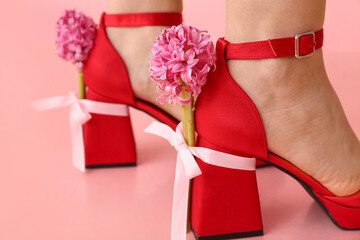 Legs of beautiful young woman in ankle straps heels with hyacinth flowers on pink background. Closeup