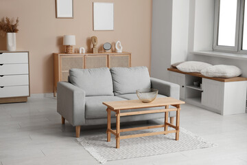 Stylish interior of living room with cozy grey sofa and coffee table