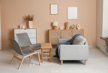 Cozy grey sofa with plaid, coffee table and chairs in living room