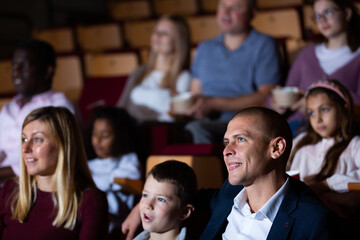 mother, father and their children sitting at comedy in auditorium