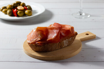 Close-up of a typical Spanish tapa of Iberian ham and seasoned olives.