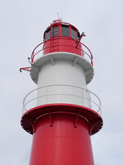 Rot-weiß gestreifter Leuchtturm an der Steuerbord Mole des Hafens Warnemünde vor der Ostsee