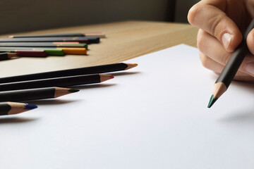 Hand holding a pencil starting to draw a picture close-up. Girl painting.