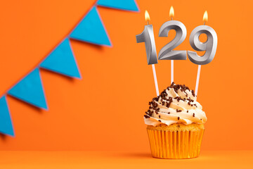 Birthday cupcake with candle number 129 - Orange background