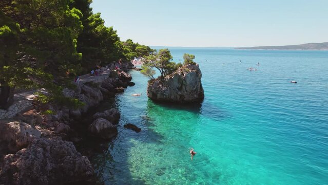 Aerial view of serene atmosphere on rocky beach with clear sea waters in summer Brela, Croatia.