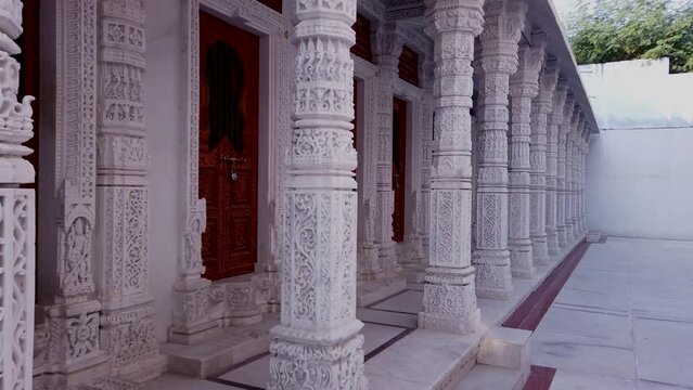 Udaipur, Rajasthan, India-October 30 2023; Artistically carved White marble pillars and wall exteriors of a Jain temple dedicated to Lord Mahavira and Parasnath at Udaipur in Rajasthan, India.
