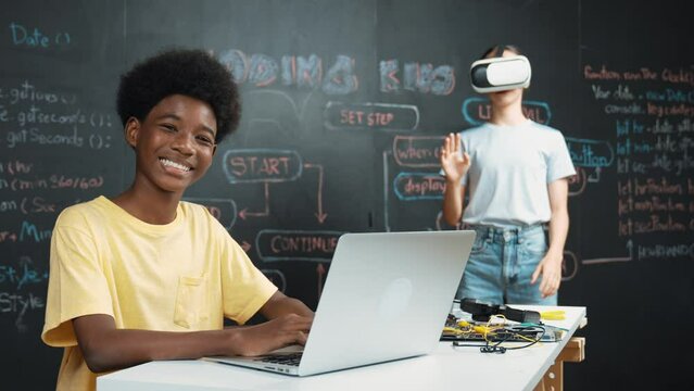 Smart african student programming and coding innovative system while caucasian girl enter in metaverse or virtual world by using VR or head set at blackboard in STEM technology classroom. Edification