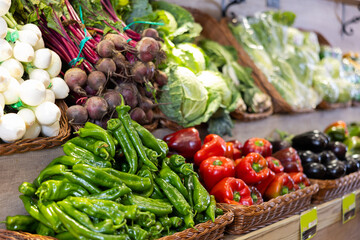 Produce stand with large colorful assortment of fresh organic vegetables arranged in woven baskets,...