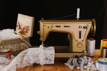 Máquina de coser antigua enhebrada y costurero con encajes, perlas, cintas y adornos