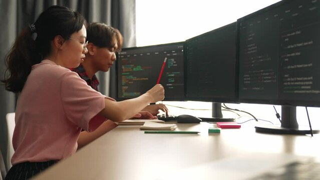 Slow motion back end software developer engineer for computer programming working together on debugging writing computing code, solving complex algorithms display on monitor in office. Burgeoning