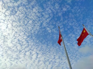 Low angle view of Chinese flag and Hong Kong flag on sky background.