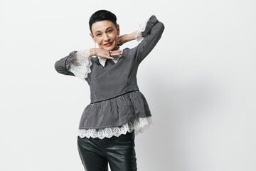 Stylish woman in black leather pants and gray blouse posing for the camera in a fashionable street...