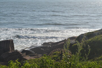 view of the sea meeting rocks on the hillside on a Brazilian beach