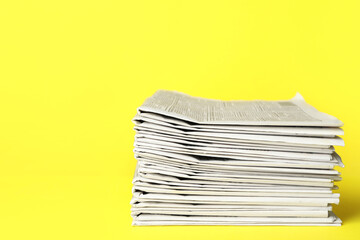 Stack of newspapers on yellow background. Journalist's work - obrazy, fototapety, plakaty