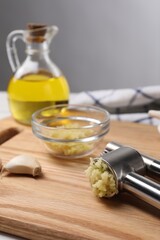 One metal press and garlic on table, closeup