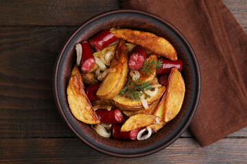 Delicious baked potato with thin dry smoked sausages, onion and dill in bowl on wooden table, top view
