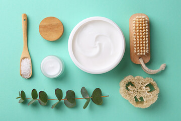 Fototapeta na wymiar Jars of cream, body care products and eucalyptus branch on turquoise background, flat lay