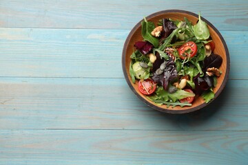 Tasty fresh vegetarian salad on light blue wooden table, top view. Space for text