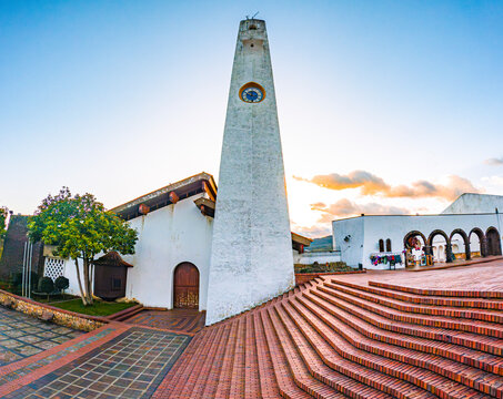 Sunset at Guatavita, Cundinamarca with a white tower, vibrant sky, and architectural beauty