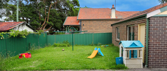 Magpie bird walking amongst toys spread all over a suburban Sydney backyard NSW Australia