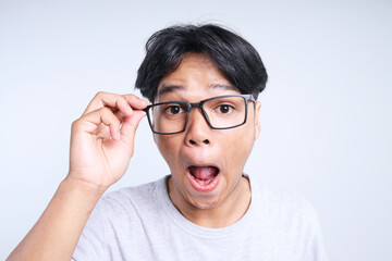 Closeup of young Asian man wearing eyeglasses and showing funny face