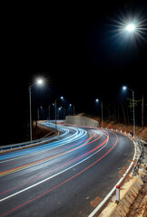 Night scene at the newly widened curved pass in Da Lat, Vietnam illuminated by the headlights of passing cars on a dark night to help traffic flow more smoothly when tourists come here