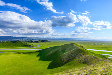Green grassland and curved river with mountain natural landscape in Xinjiang