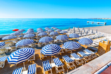 Turquoise sea, blue and white umbrellas, lounge chairs, and the pebble beach along the Promenade des Anglais, at the Cote d'Azur French Riviera, in Nice, France. © Kirk Fisher