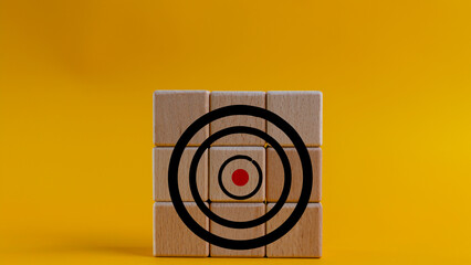 Target icon on wooden cubes, yellow background. Target concept