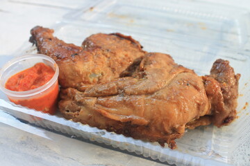 Indonesian dish called ayam bacem and sambal in plastic mica on the table