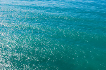 Aerial view of turquoise sea water surface with small rocks