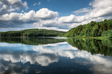 Beautiful summer landscape with lake, forest and clouds reflected in water