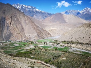valley with farm field enveloped by mountains with a majestic river meandering through its serene landscape.