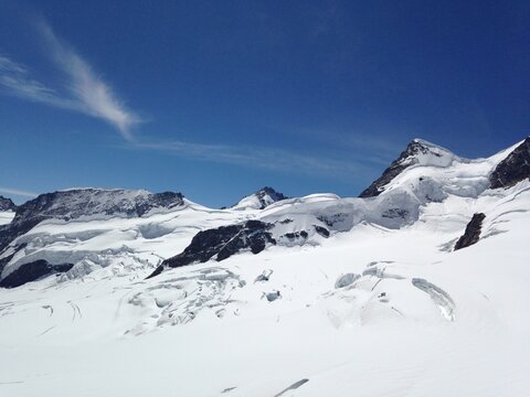 The image features a snowy mountain in Jungfraujoch, Switzerland, set against a clear blue sky