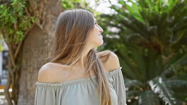 Blissful young woman in an off-shoulder top enjoying nature in a lush park