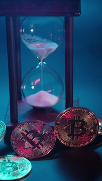 Golden bitcoin on the background of an hourglass. cryptocurrency, money and time. Physical bitcoin and hourglass shows that the time is up. Crypto currency, virtual money. Vertical shot.