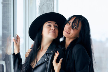 2 Beautiful sexy women posing against the window in black jackets - 752695806