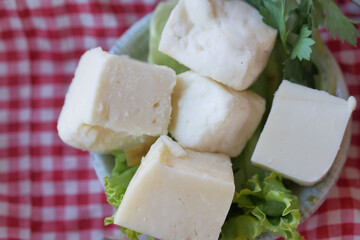 Food plate of cheese cubes and lettuce on checkered tablecloth