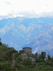 A charming house perched on a scenic hill, framed by majestic mountains in the backdrop, offering serene beauty.