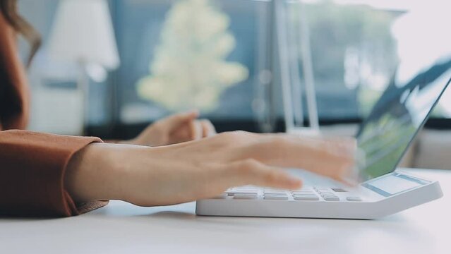 Closeup image of a business woman's hands working and typing on laptop keyboard on glass table.