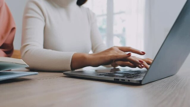 Closeup image of a business woman's hands working and typing on laptop keyboard on glass table.
