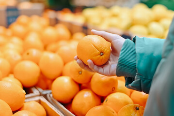 Buying fruit, close-up of a woman buyer choosing oranges in a store