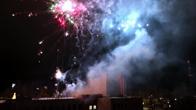 Colorful fireworks display illuminating the night sky behind a dark, monolithic building