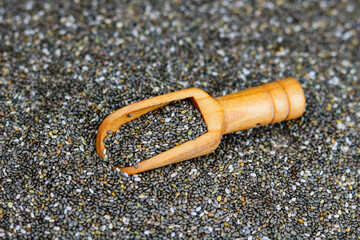 Chia seeds in a wooden scoop on a background of chia seeds