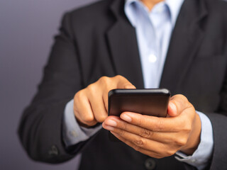 Businessman using a smartphone while standing on a black background.