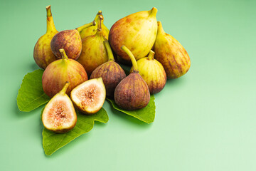 Top view of figs fruit with fresh leaves on a green background.