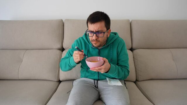 Man eating in the sofa after dental procedure with difficulty to open the mouth