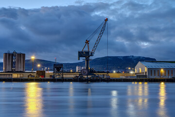 A loading crane and storehouses in the port of Belfast at twilight