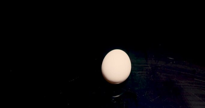Easter is coming soon. One chicken egg white is spinning on a black background. 