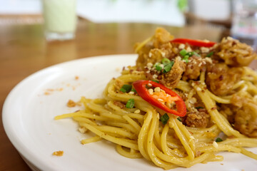 Spaghetti with chicken popcorn topping served in white plate, ready to eat